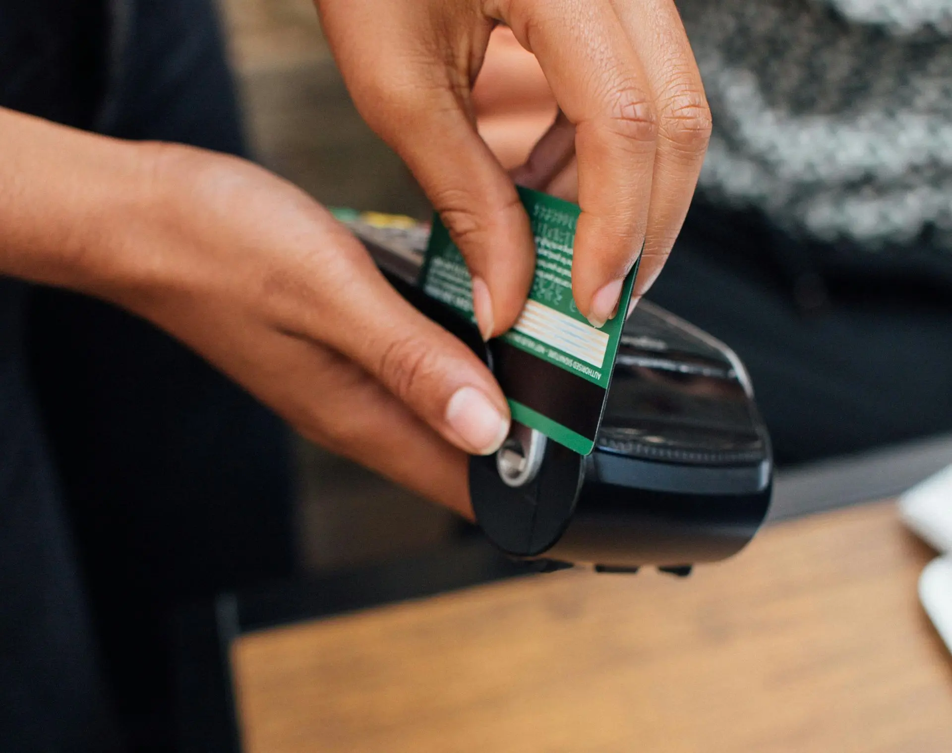 Main insérant une carte bancaire dans un terminal de paiement, illustrant la fraude au remboursement avec une carte volée ou un faux TPE