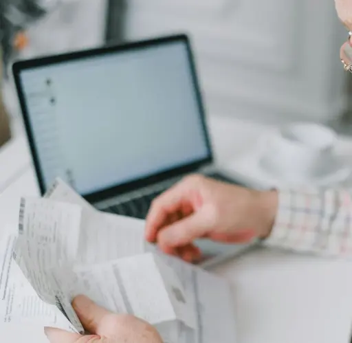 Commerçant vérifiant tickets papier et version numérique sur ordinateur pour double conservation 3 ans